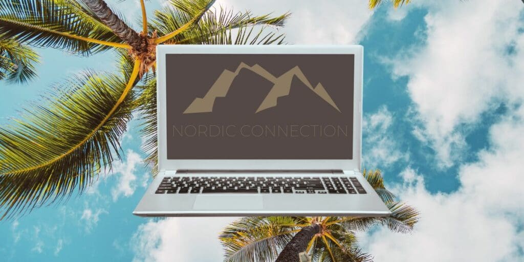 Laptop på bord ved stranden på Gran Canaria med palmer og moderne kontorutsikt i bakgrunnen, som representerer fjernarbeid kombinert med ferie.